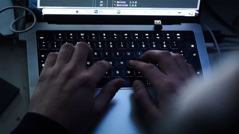 Hands typing on a computer keyboard.