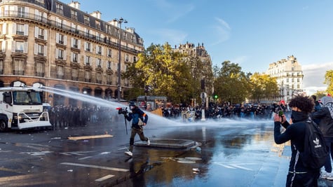 Videographer runs through water cannon while student films with phone
