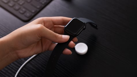 Hand holding Apple Watch charger