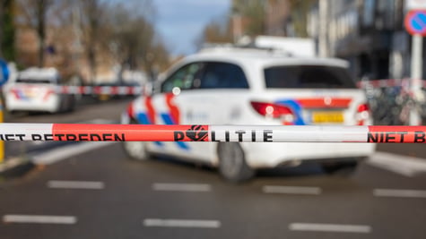 police security tape reading "politie" in Dutch; police car in the background