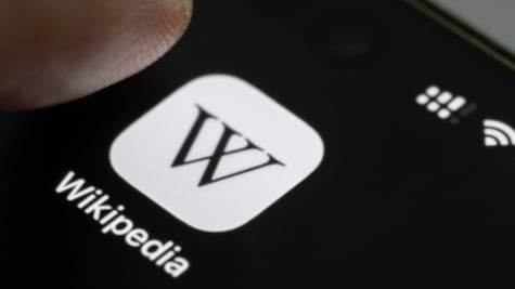 Finger press Wikipedia app icon close up view on smartphone screen