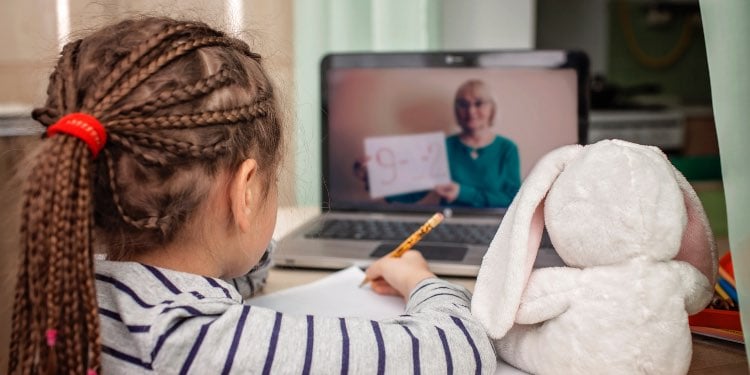 Girl studying and looking at teacher on laptop screen