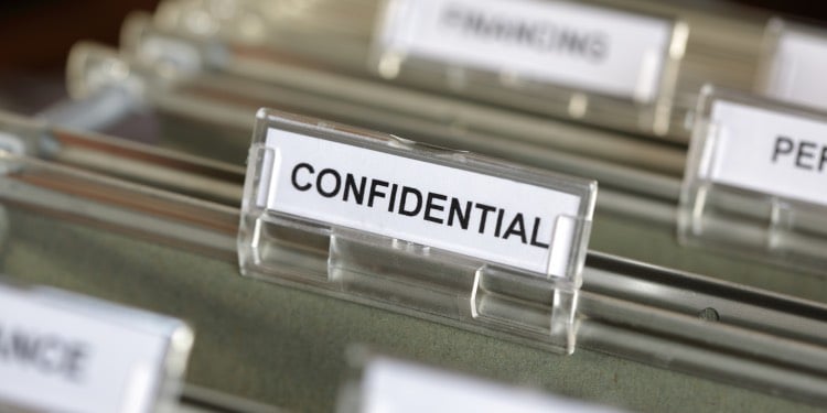 Inside of a filing cabinet with green folders and focus on confidential label