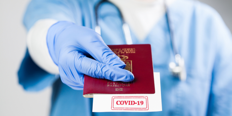 Doctor holding passport with COVID-19 sign stamped onto white paper