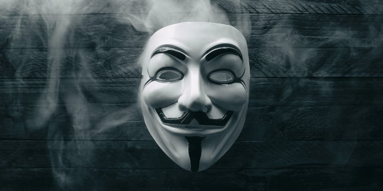 Studio shot of a Anonymous Vendetta mask with smoke on wood