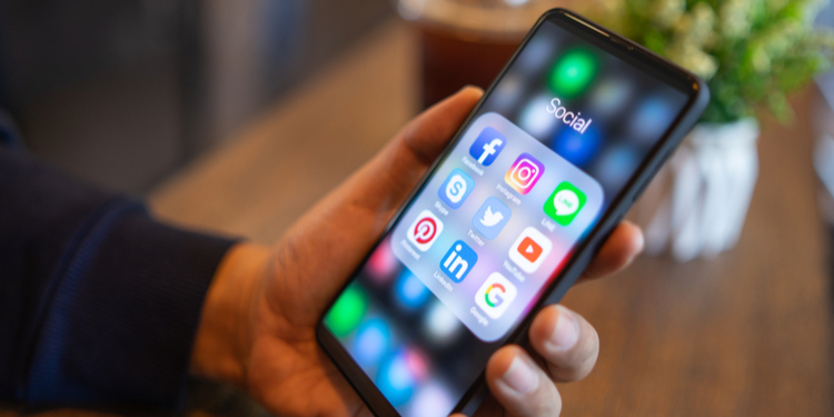 Man holding mobile with icons of social media on the screen