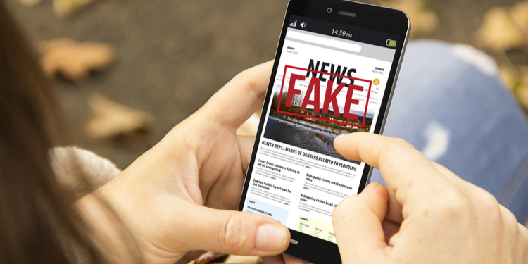young woman with smartphone reading fake news at the park