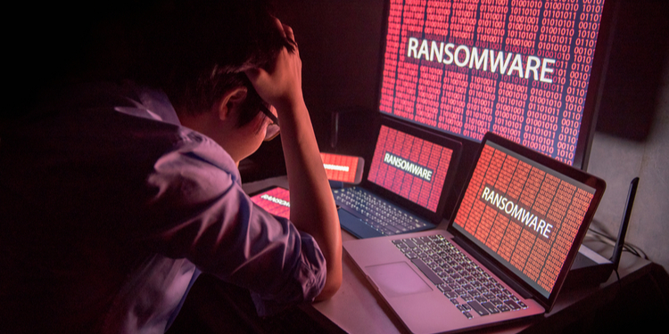 Young Asian male frustrated, confused and headache by ransomware attack on desktop screen