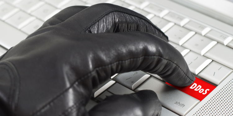 Gloved hand clicking DDoS button on keyboard