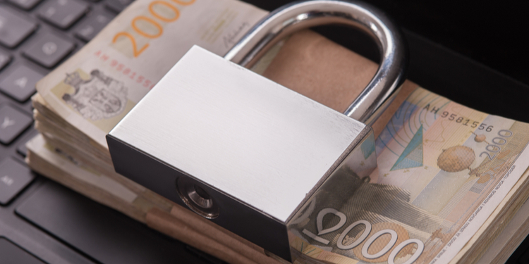 Pile of money with padlock on laptop keyboard. Ransomware