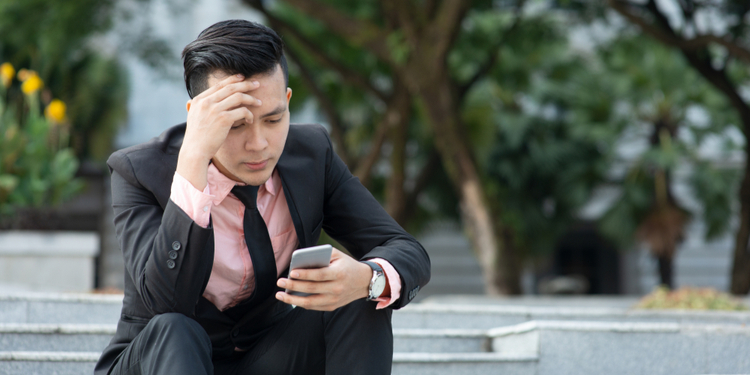 Man looking at mobile phone with serious face, negative emotion, phishing scams concept.