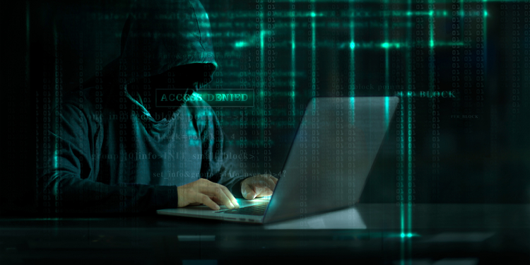 Hooded person using laptop in a matrix background