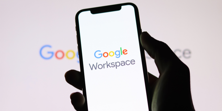 Shadowy hand holding mobile phone with Google Workspace logo on it