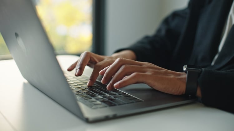 A close-up of hands type laptop keyboard