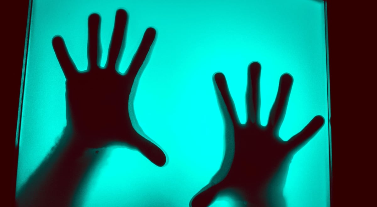 Hands behind a computer screen