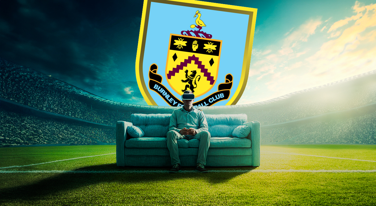 man sitting on a light blue sofa n the middle of a football stadium, crowd, green grass