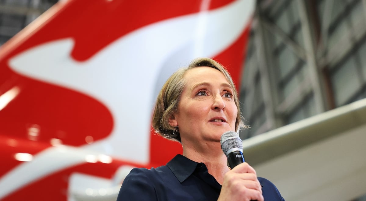 Qantas CEO Vanessa Hudson speaking to a microphone next to a plane