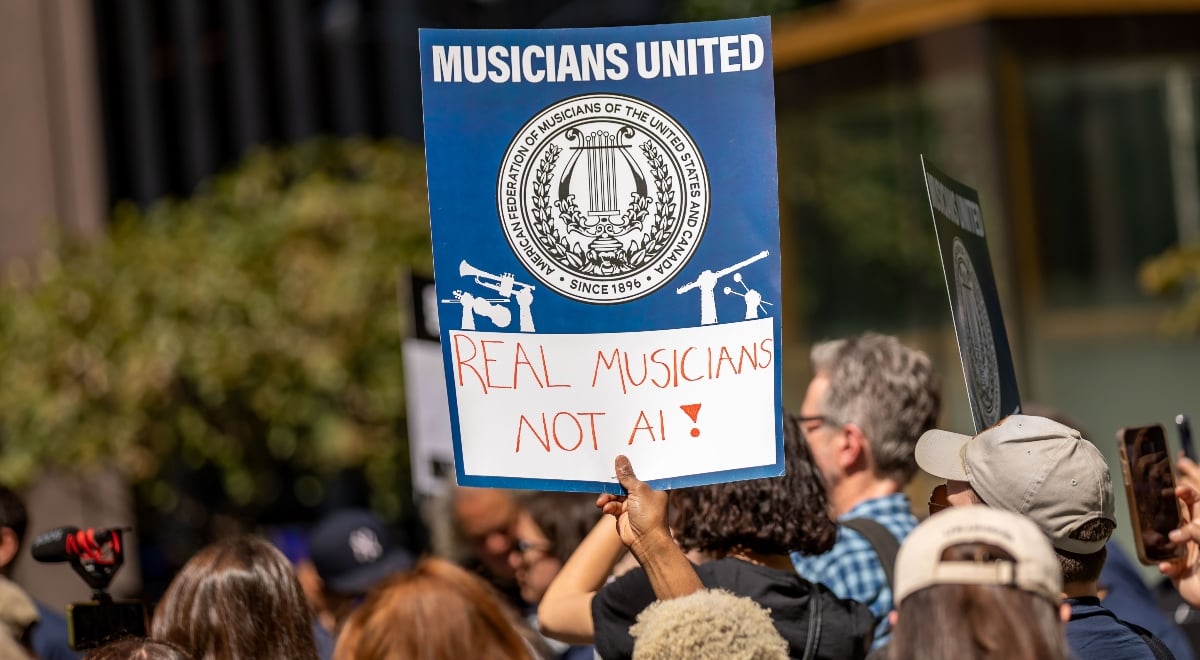 Protestors hold a poster saying "Real musicians not AI"