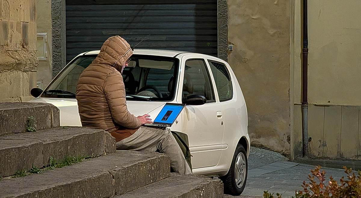 man working on laptop sitting outside on stairs