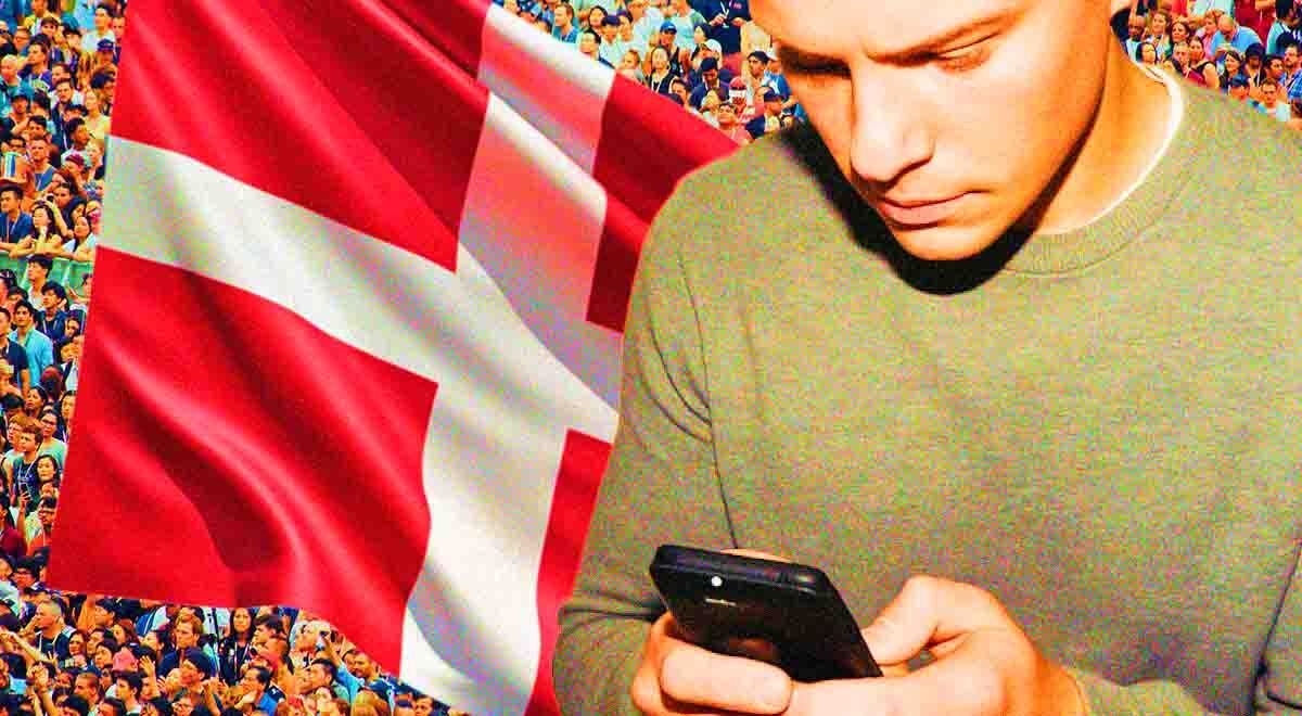 A person using a smartphone and Danish flag behind him
