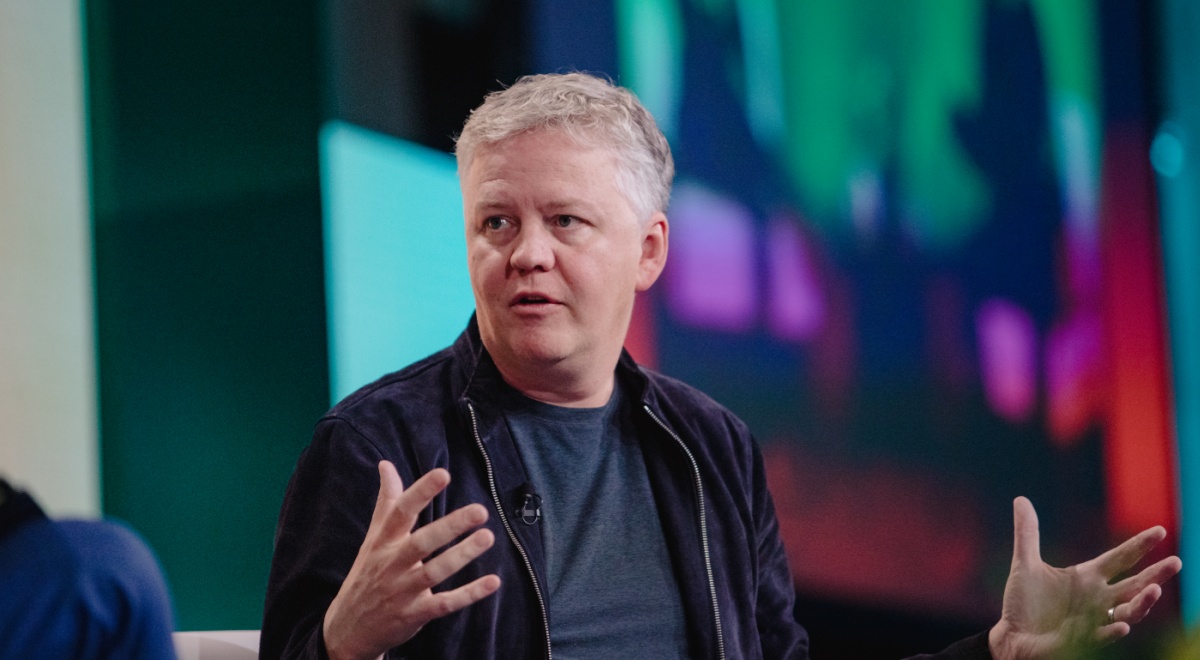 Cloudflare CEO Matthew Prince black suit, grey shirt, no collar, white hair, head turned left