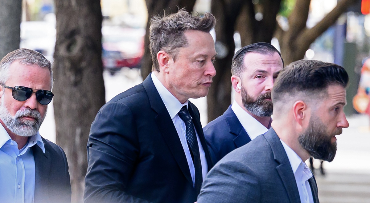 elon musk, profile, walks down the street, three body guards in suits