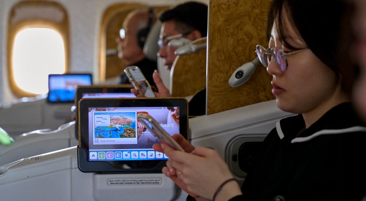 asian woman looks at her phone, black hair, tiny television screen, more passengers in the back