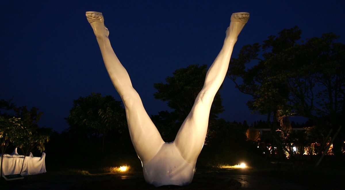 white spread legs in the dark blue night sky, warm lit sculpture