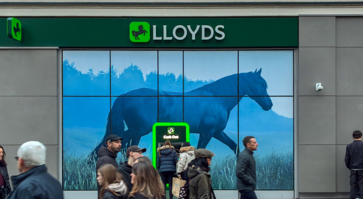 lloyds bank, green logo, people passing by, black horse logo, grey wall, warm people's outfits