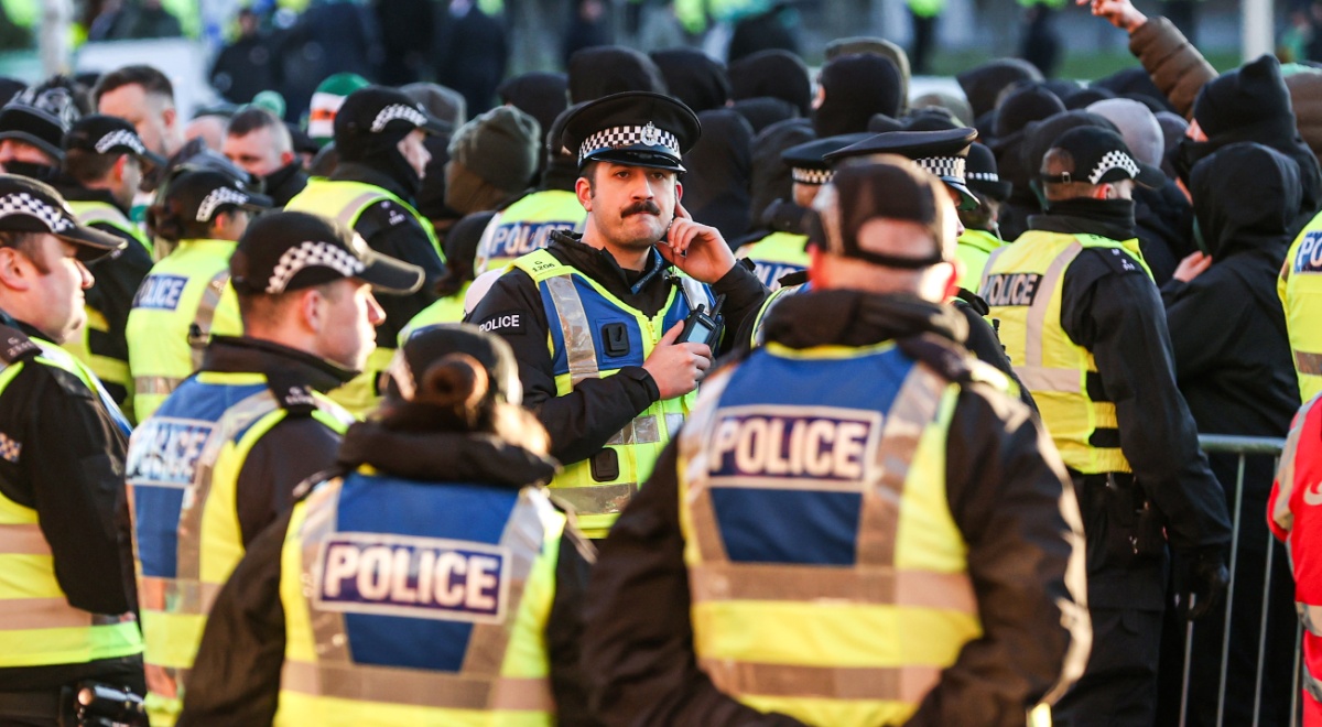 Police officers in yellow reflective rests, black hats with white squares, blue police signs