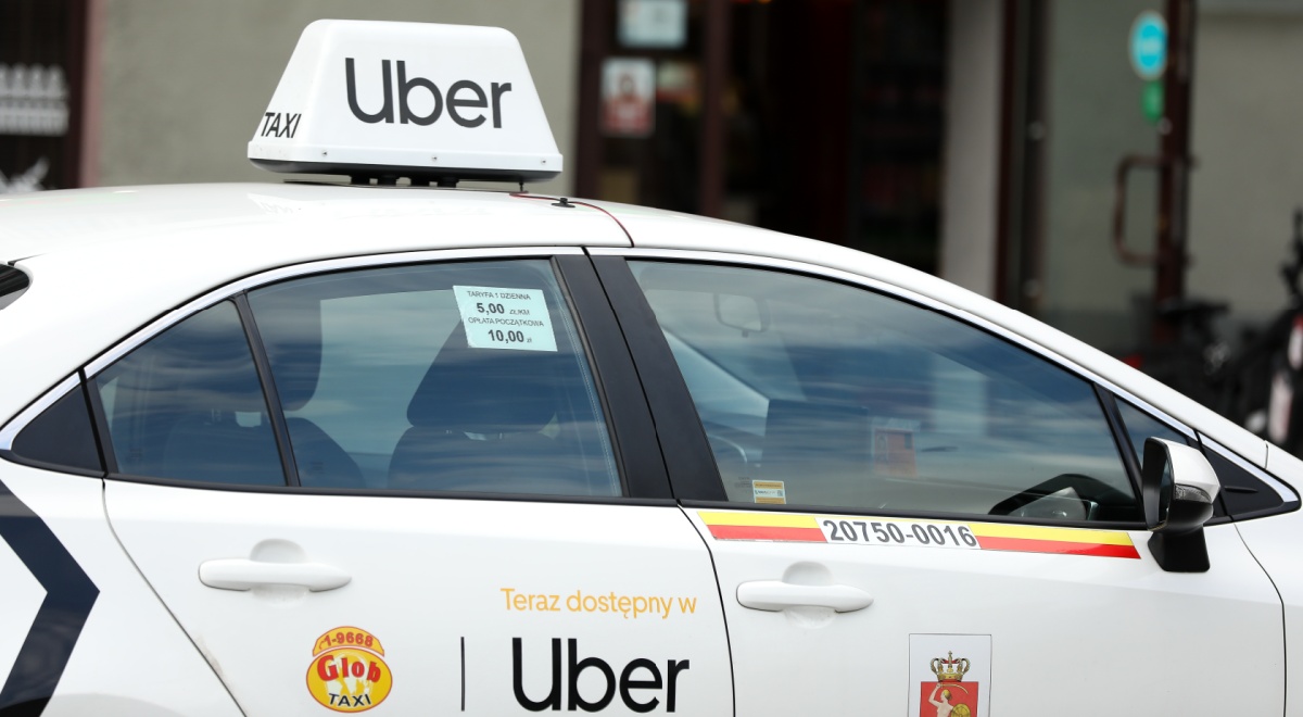 white uber car with sing on door, on top of roof
