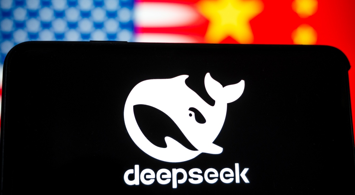 DeepSeek app logo with white whale on black phone screen, blurry US and China flags in the back