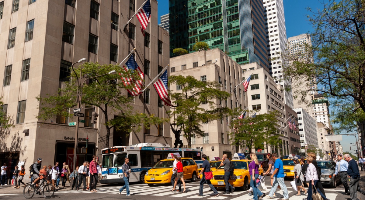 fifth avenue, sunny day, blue sky, tall buildings, pedestrians crossing street, yellow taxis,