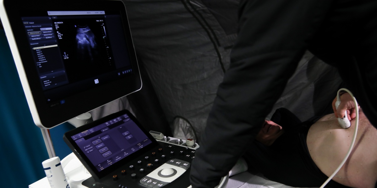 black shirt, ultrasound examination, white bald patient, naked belly, black monitor