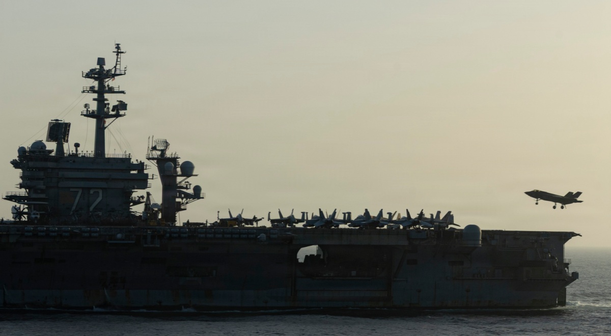 USS Abraham Lincoln (CVN 72) war ship at sea during sunset, plane in sky, plane fleet onboard,
