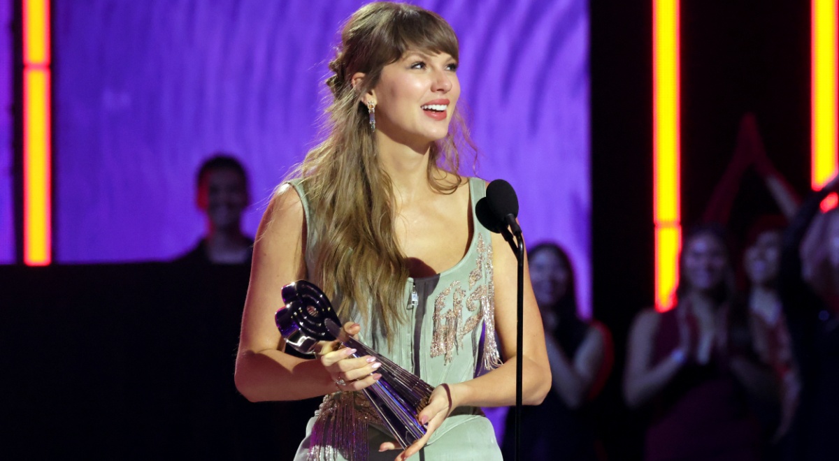 taylor swift, dark blonde almost loose hair, wavy, award statue in hand, grey-greenish strap dress
