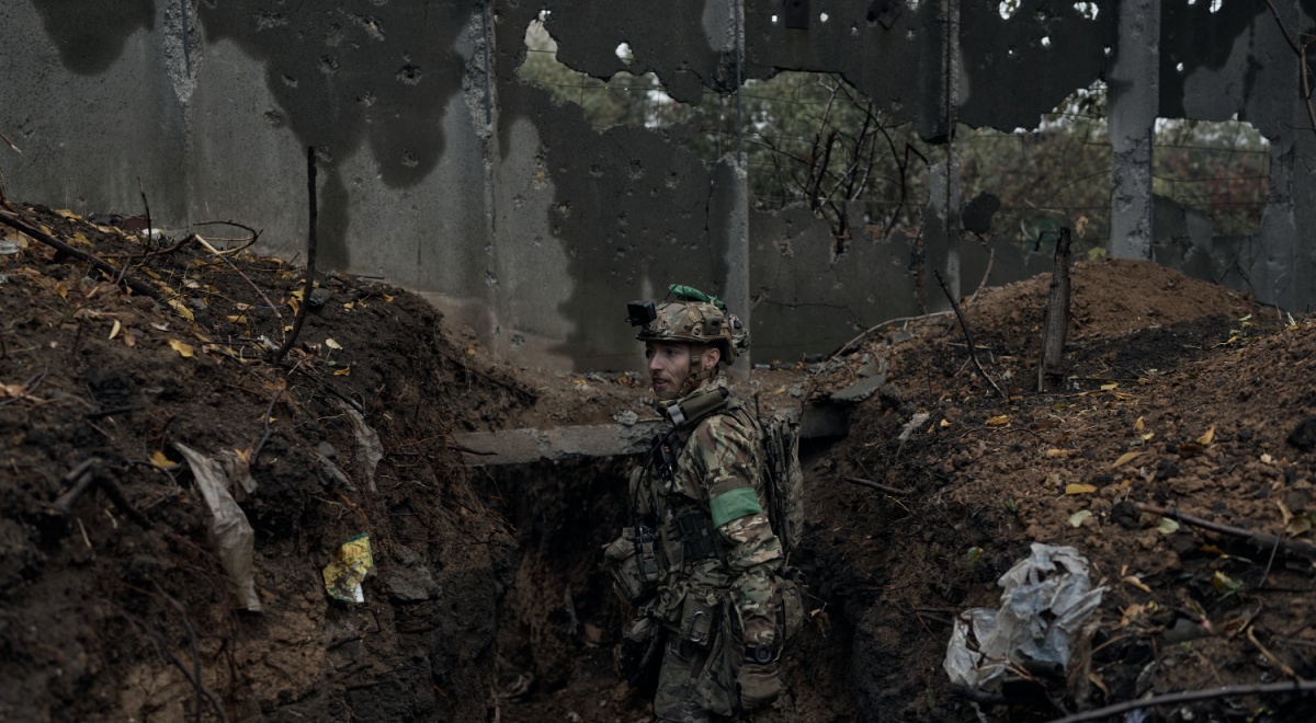 ukrainian soldier in muddy trench, uniform, muddy face, ruins around, gun on shoulder, helmet