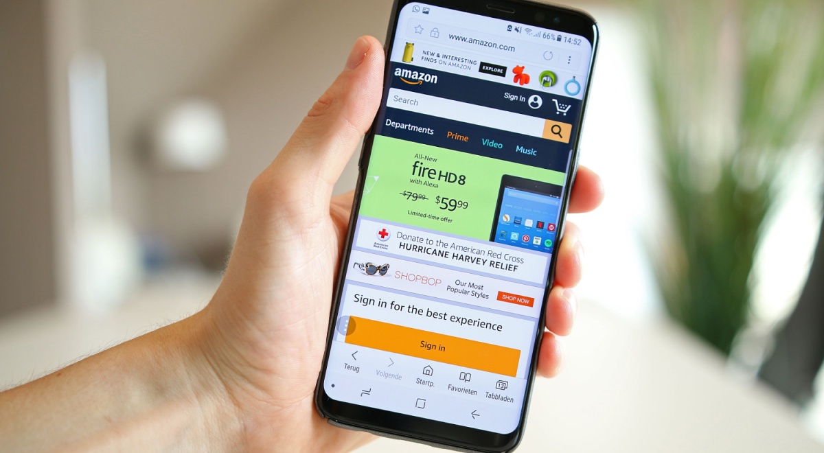 A hand holds a smartphone with an open Amazon page