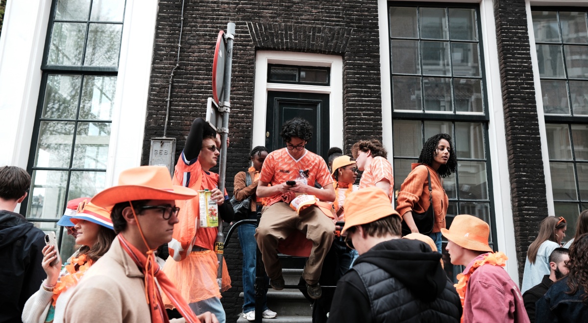 people dressed in orange, amsterdam streets, man on phone, sits on stairs, big windows