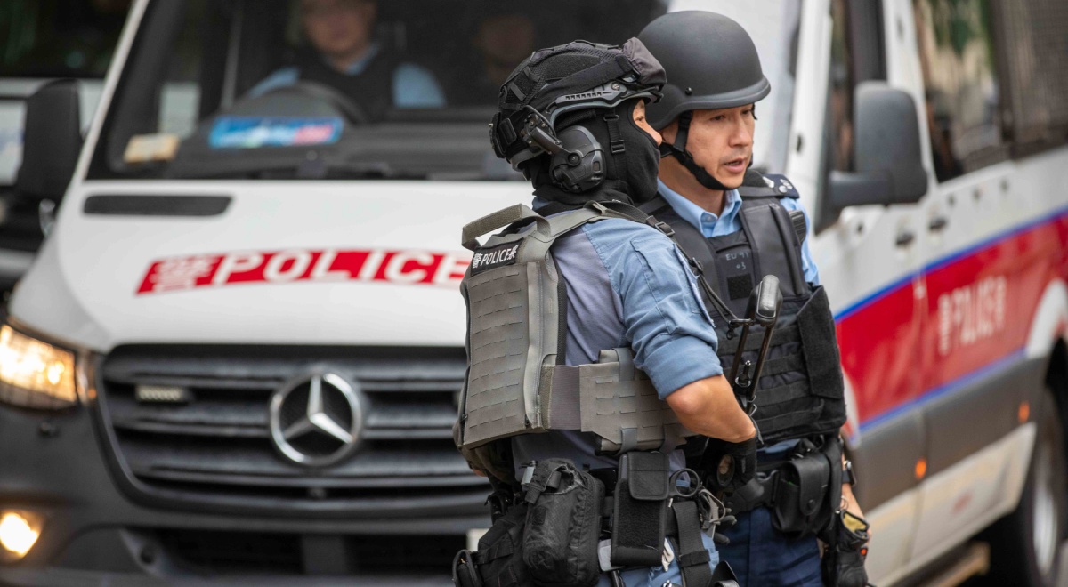 hong kong, two male policemen, white police van, blakc bulletproof vests, blue shirts, black helmet