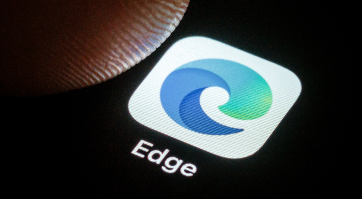 microsoft edge blue-greenish icon in white background on black screen, finger tip