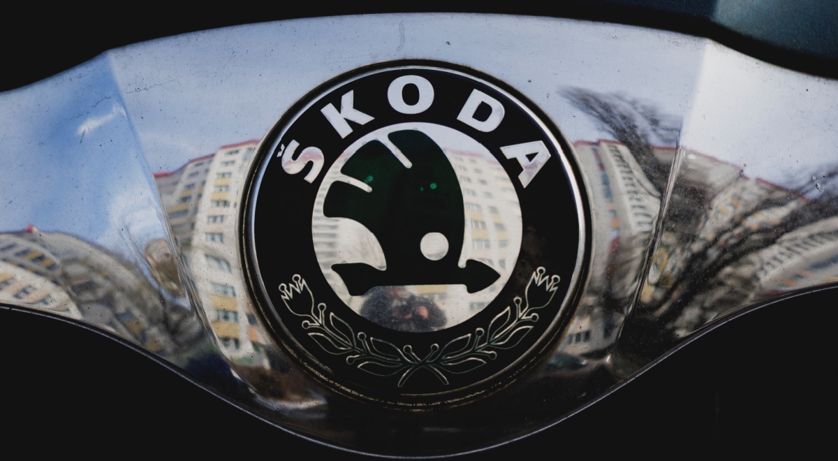 black skoda logo on a car front, reflection on buildings on silver plate, 