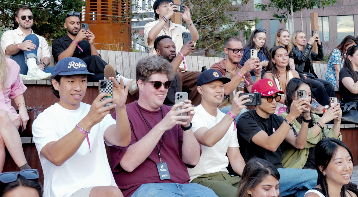 about thirty white people raising their smartphones to film, t-shirts, hats, 
