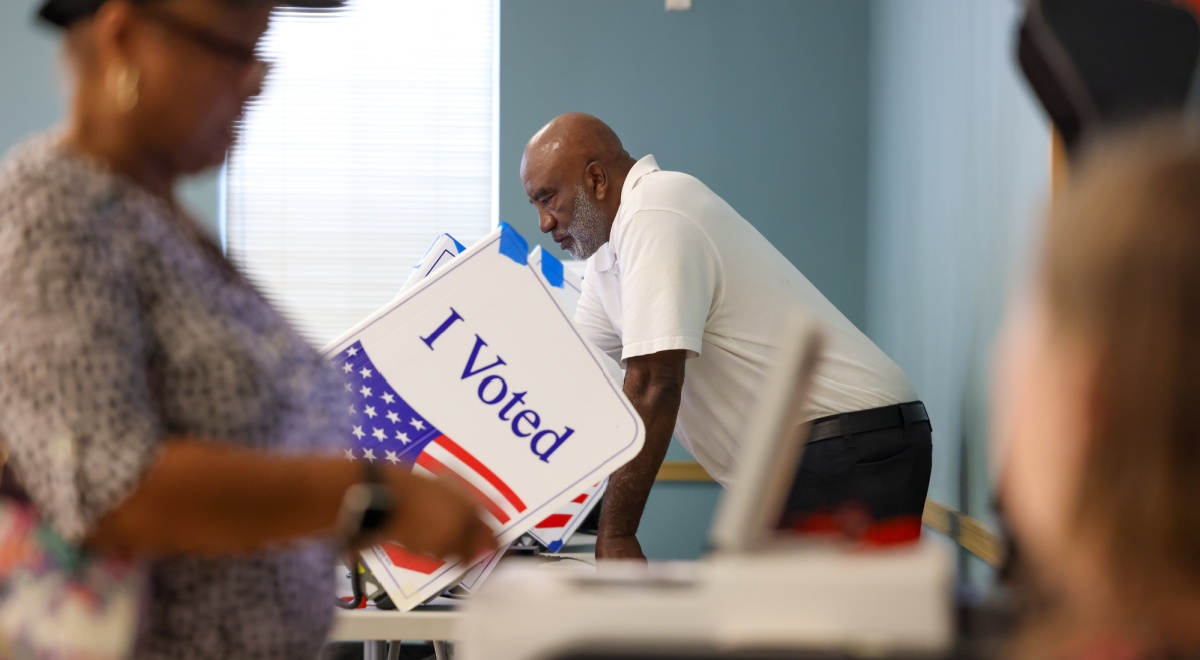 I voted sign on white paper, usa flag, black man, white shirt, black woman, black pants