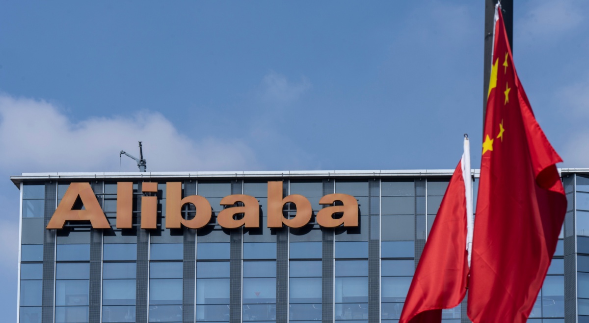 alibaba orange signage atop glass building, blue sky, white cloud, two china's flags