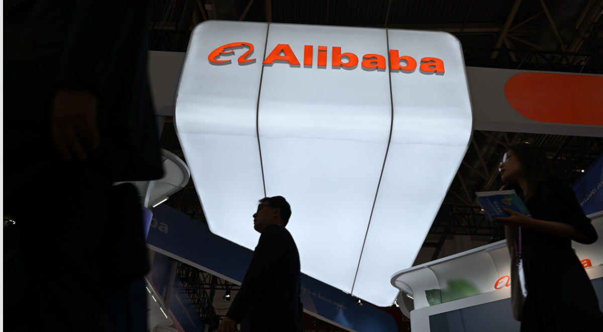 alibaba booth, white glowy sign, orange letters, two black silhouettes of asian male and female