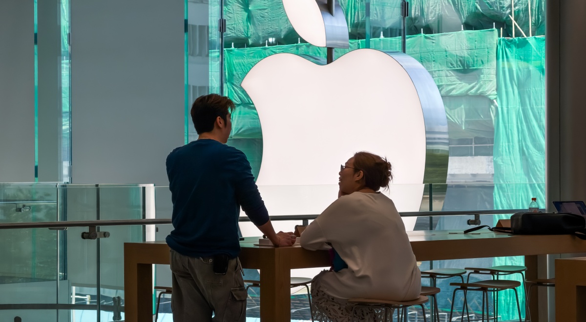 huge silver apple logo, asian man standing ,fat asian woman sitting, green background