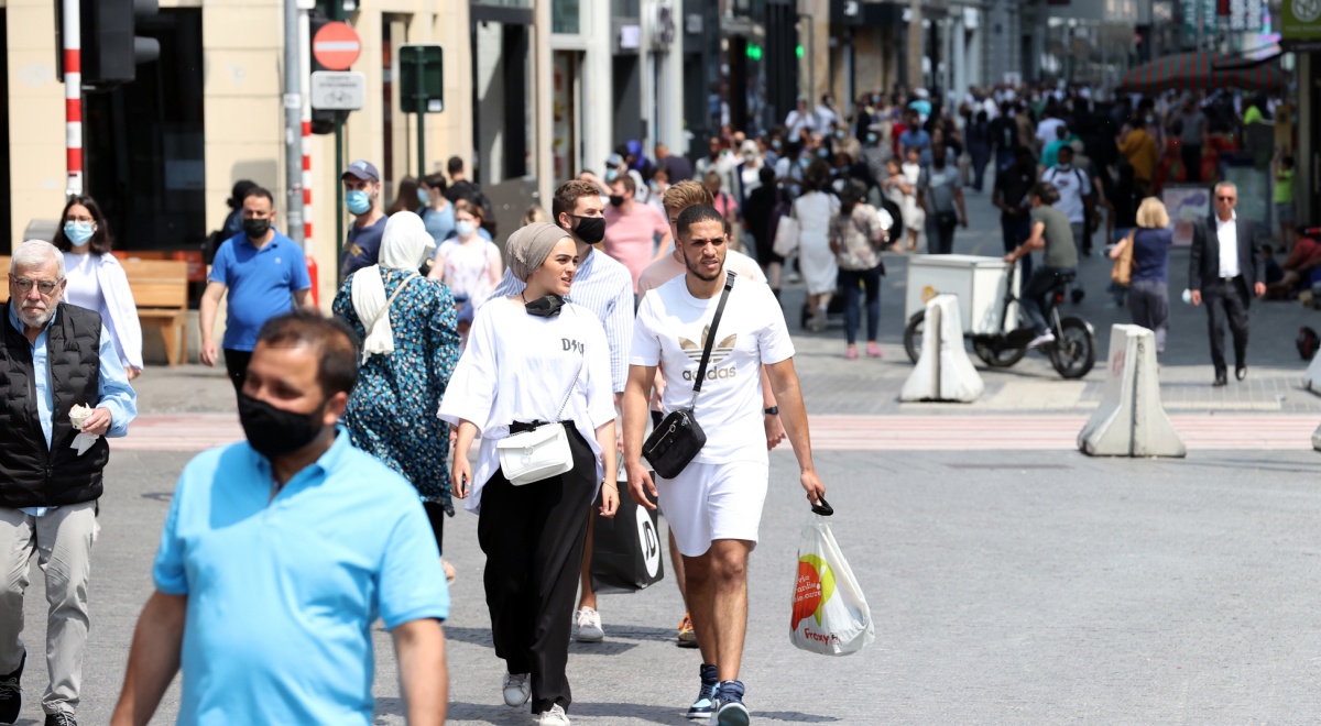sunny day, grey pavement, blue t-shirt- blue face mask, white shirts, shopping bag, white shorts