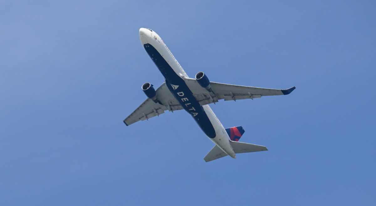 delta airline white plane in blue sky, delta sign on bottom on the plane
