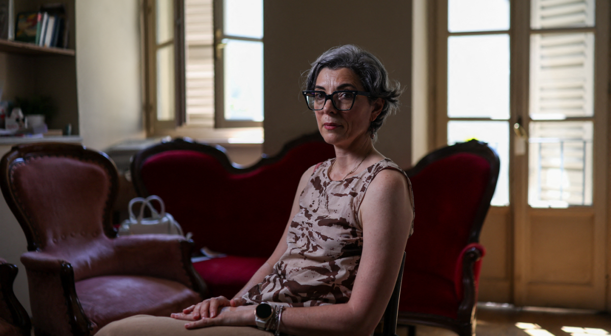 italian woman, sleevless shirt, grey hair, black frame glasses, tall windows, vintage sofa